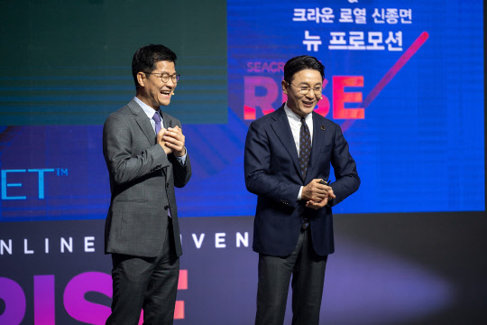 사진= 홍석우 운영총괄 상무가 신종면 크라운 로열과 함께 '2021 시크릿 온 라이즈' 온라인 컨벤션 무대 위에서 신규 프로모션을 설명하고 있다.